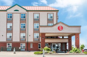 Un hotel de varios pisos con techo rojo y un logotipo rojo destacado en la entrada.