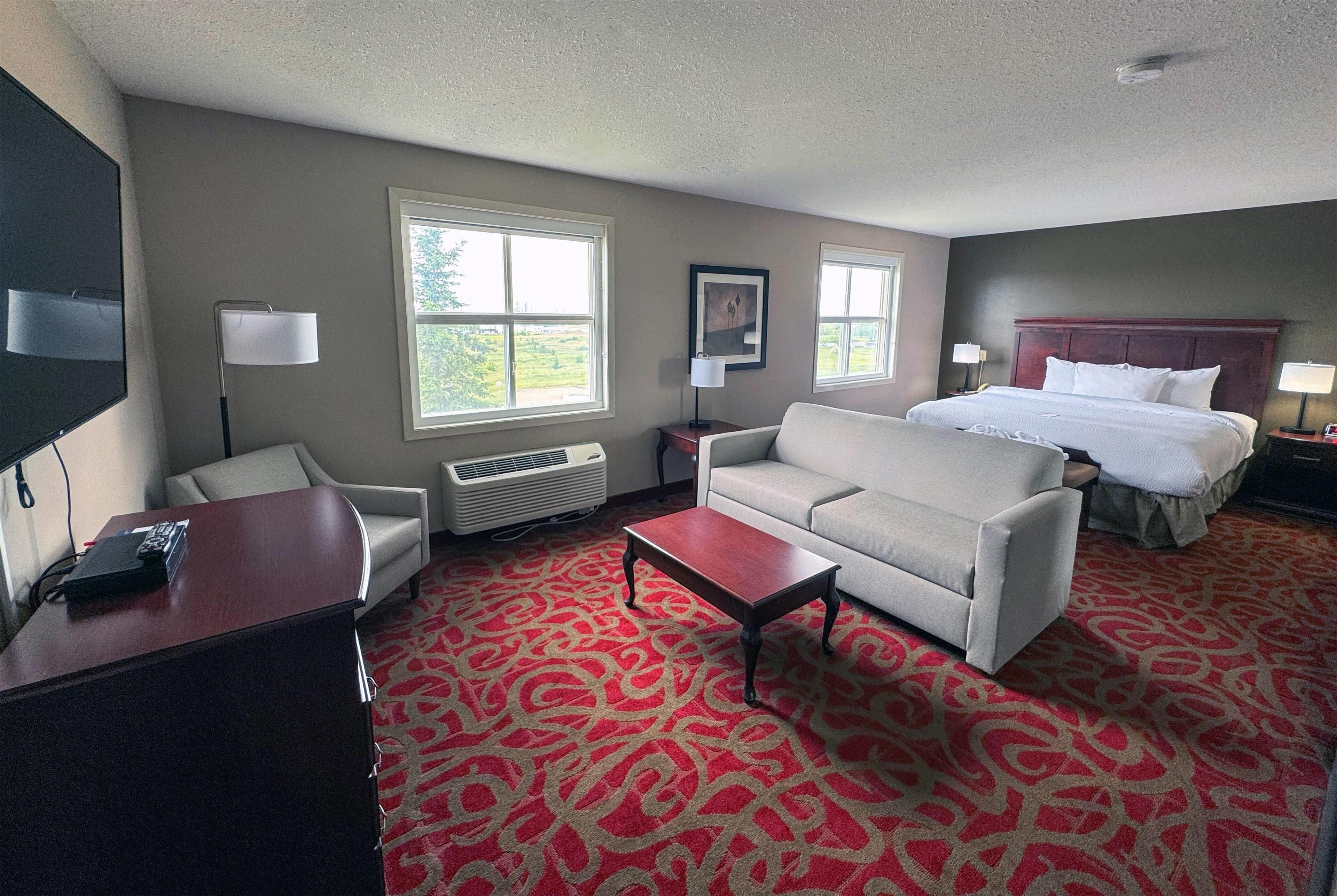 Una habitación de hotel con una cama, un sofá, un escritorio y un televisor.