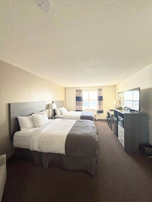 Een hotelkamer met twee bedden, een bureau, een stoel, een dressoir en een televisie.