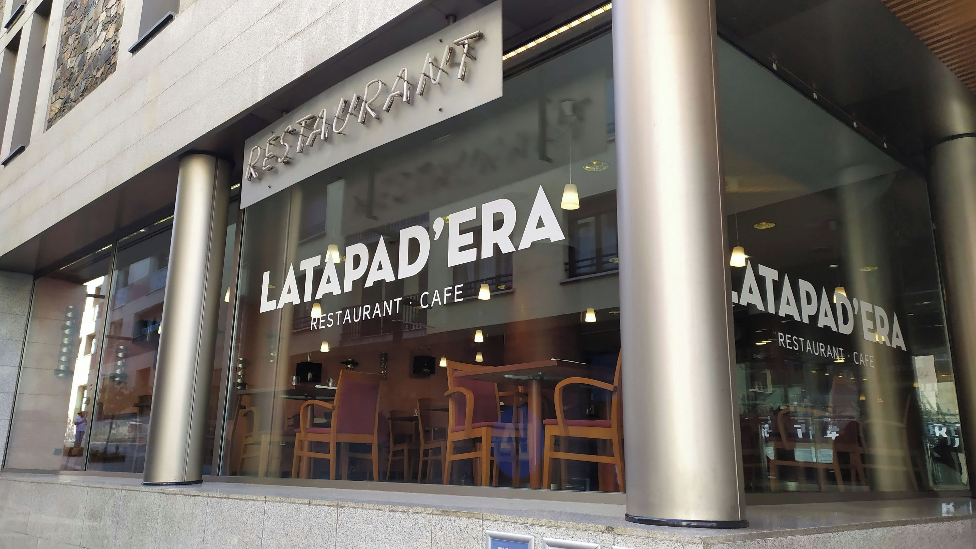 A restaurant with a modern design, featuring large glass windows and metal columns.