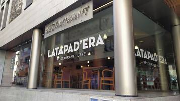 A restaurant with a modern design, featuring large glass windows and metal columns.