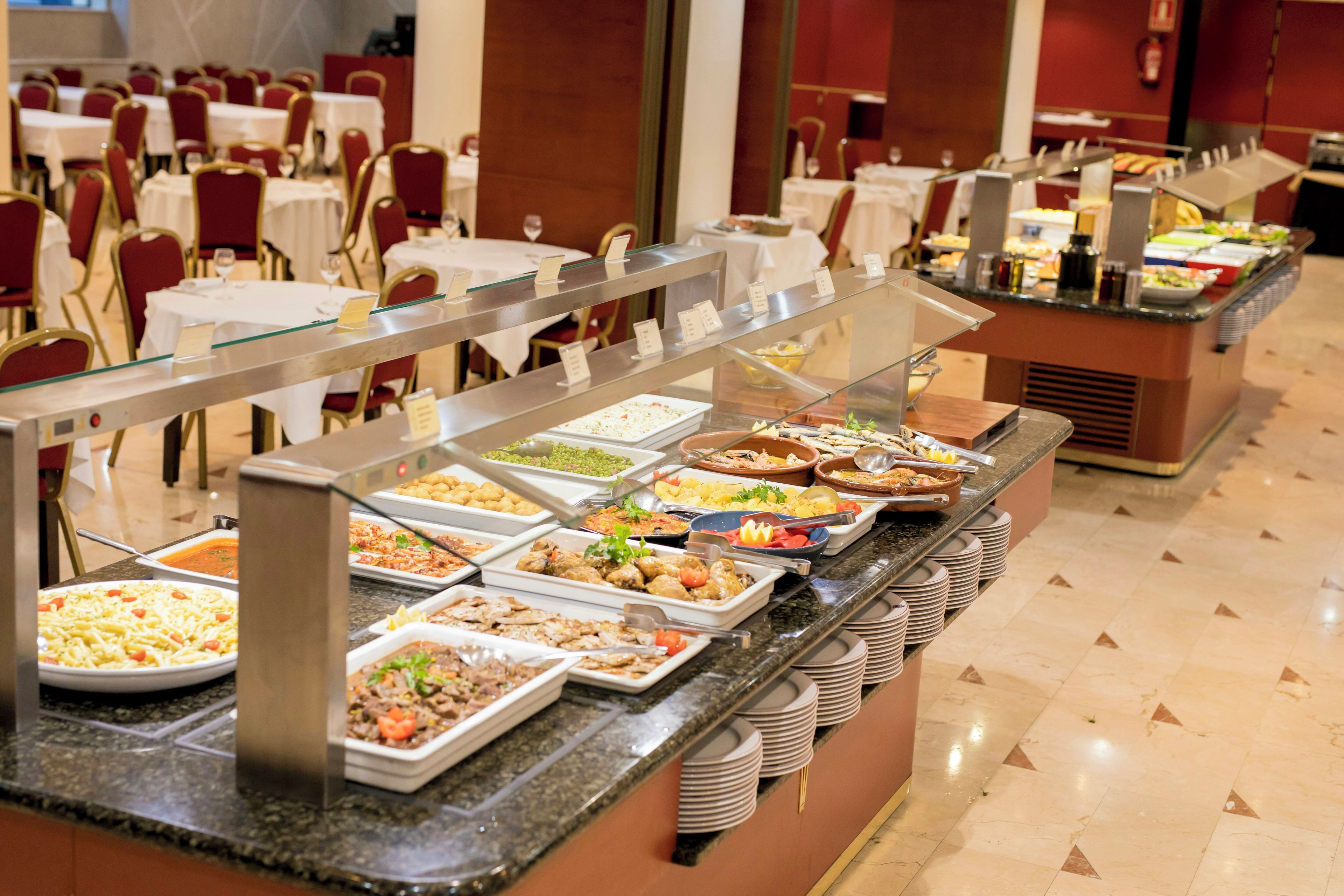 Un buffet avec plusieurs présentoirs de nourriture et un espace repas comprenant des tables et des chaises.