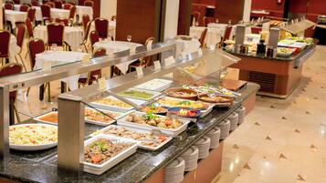 Un buffet avec plusieurs présentoirs de nourriture et un espace repas comprenant des tables et des chaises.