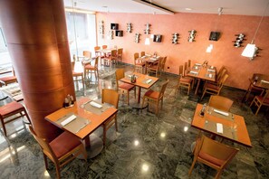 A restaurant with multiple tables and chairs, marble flooring, and a wall with wine bottles displayed. - Sercotel Delfos Andorra (Escaldes-Engordany)