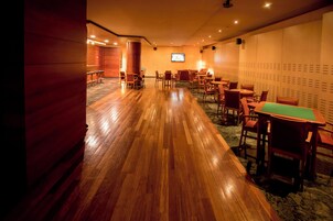 Un hall de hotel con suelo de madera, zonas de estar y una pantalla de televisión.