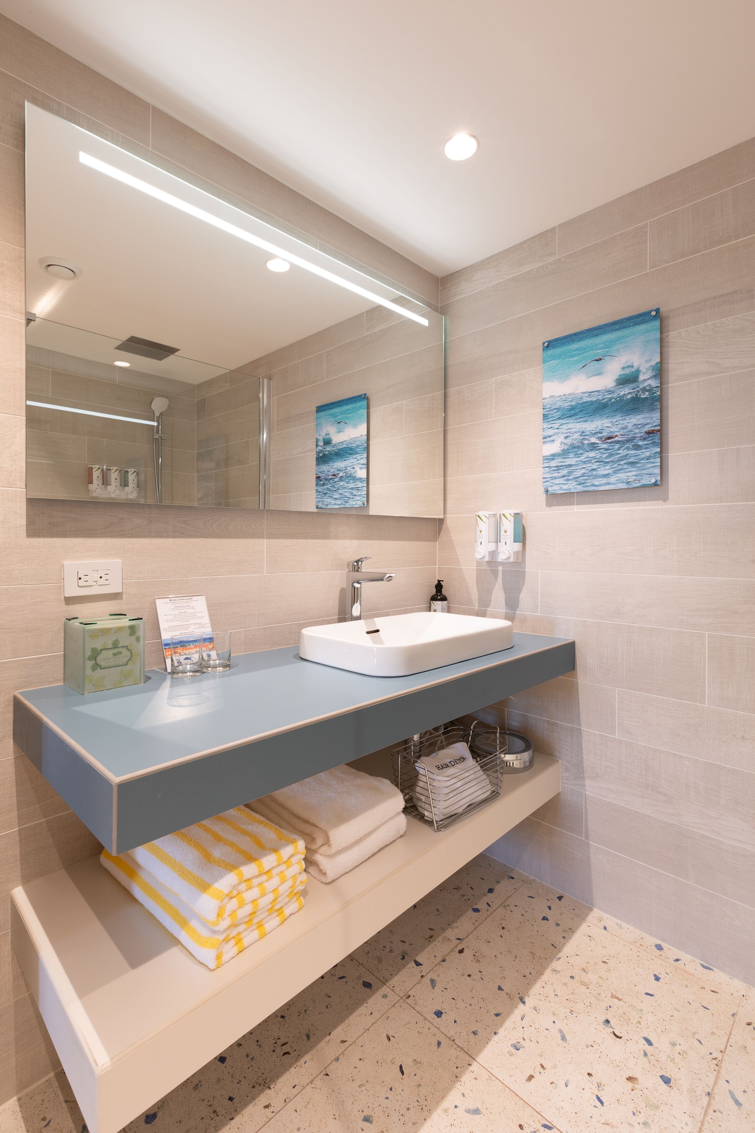 Un baño moderno con un espejo grande, un lavamanos y un perchero para toallas.