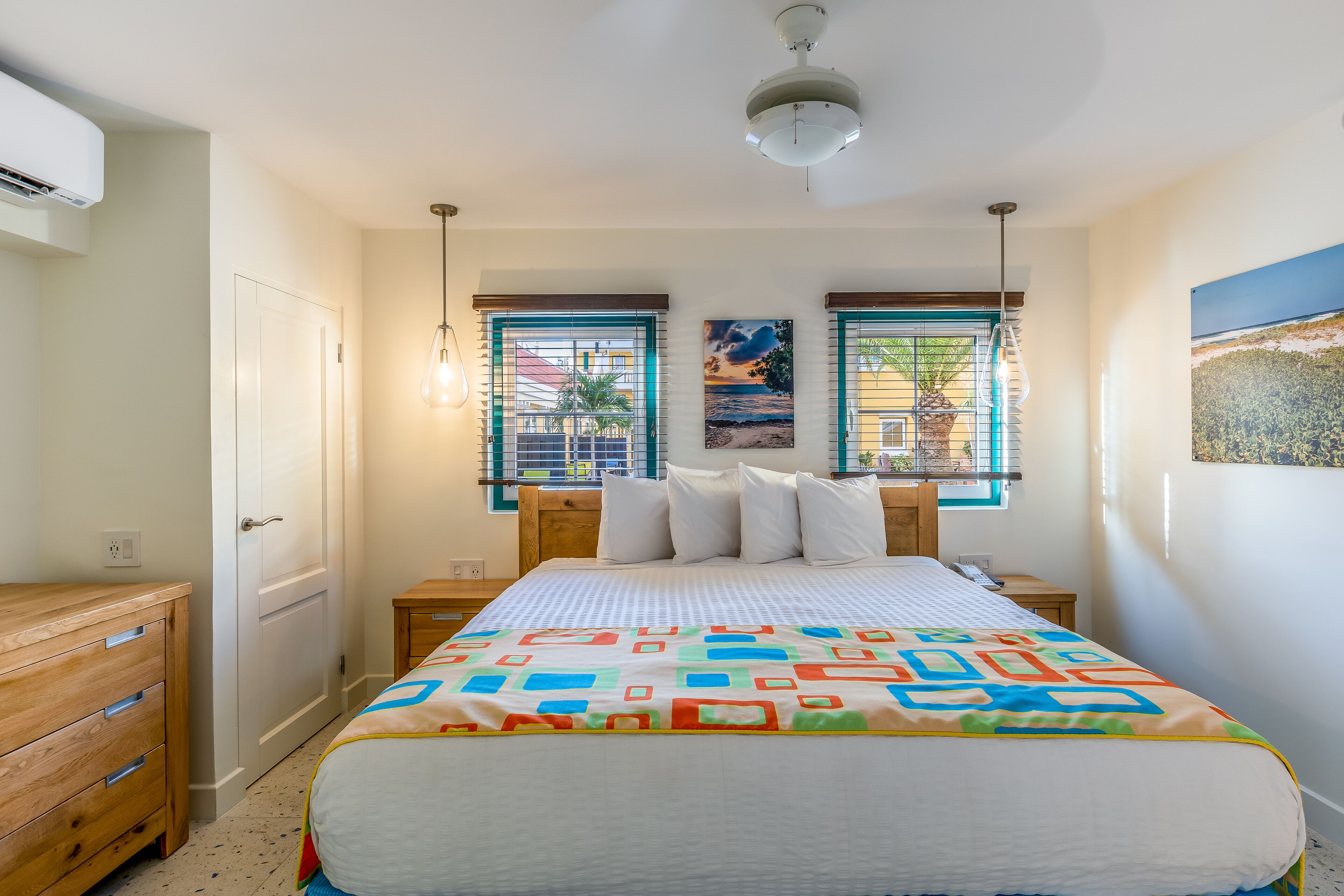 A bedroom with a bed, bedside tables, a dresser, and a window with blinds.