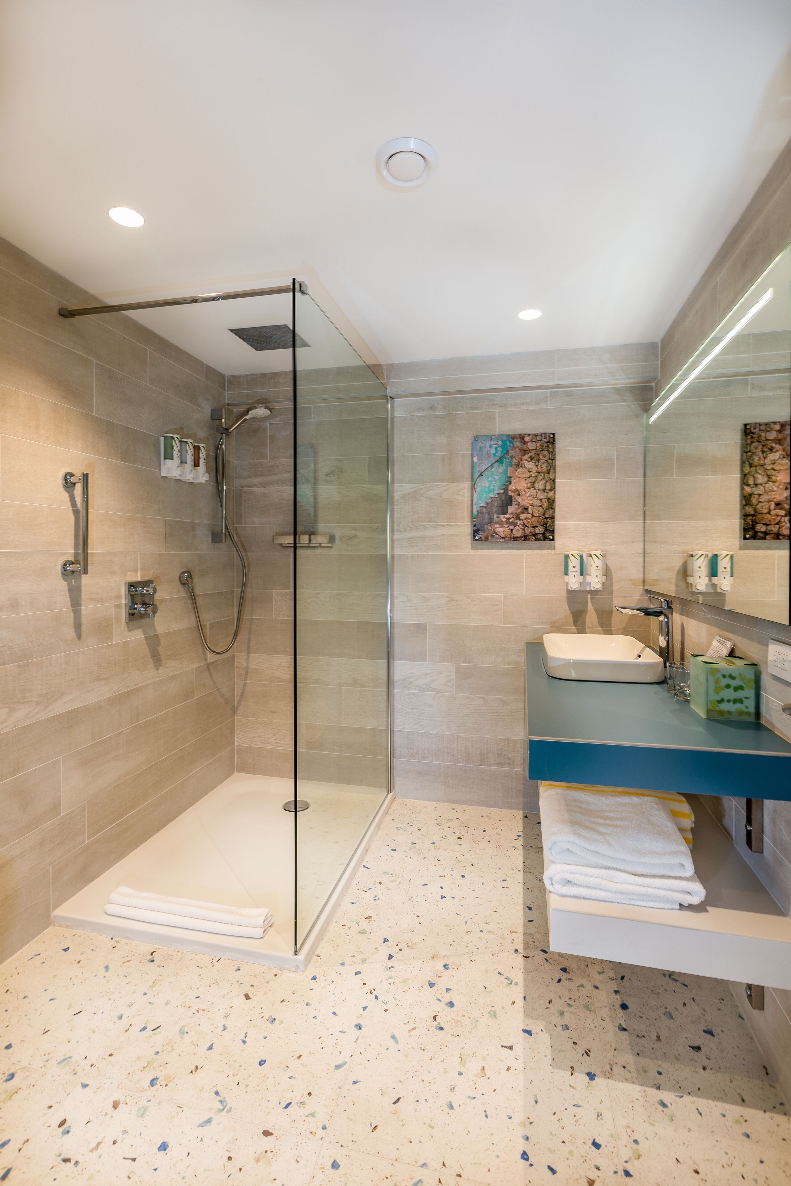 Une salle de bain moderne avec une douche à parois de verre, un lavabo avec un miroir et un porte-serviettes.