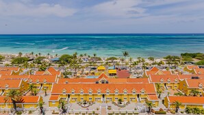 A coastal resort with yellow buildings, a beach, and the ocean. - Amsterdam Manor Beach Resort (Noord)