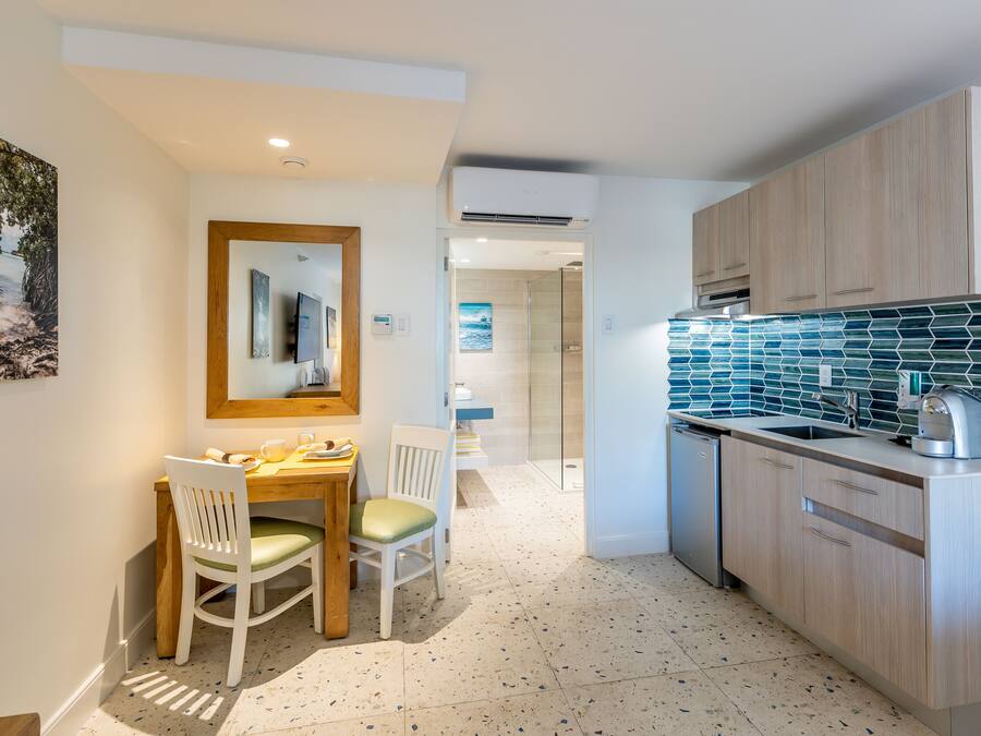 Una cocina moderna con armarios de madera, salpicadero de azulejos y un comedor con mesa y sillas.