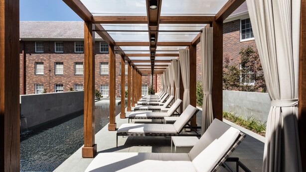 A rooftop lounge with sun loungers, wooden beams, and a view of a brick building. - Brassey Hotel (Barton)