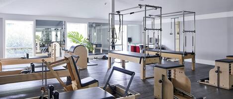A Pilates studio with wooden equipment, large windows, and a modern interior.