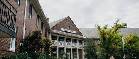 A hotel with a brick facade, a balcony with white railings, and a sign reading "Brassey Hotel".