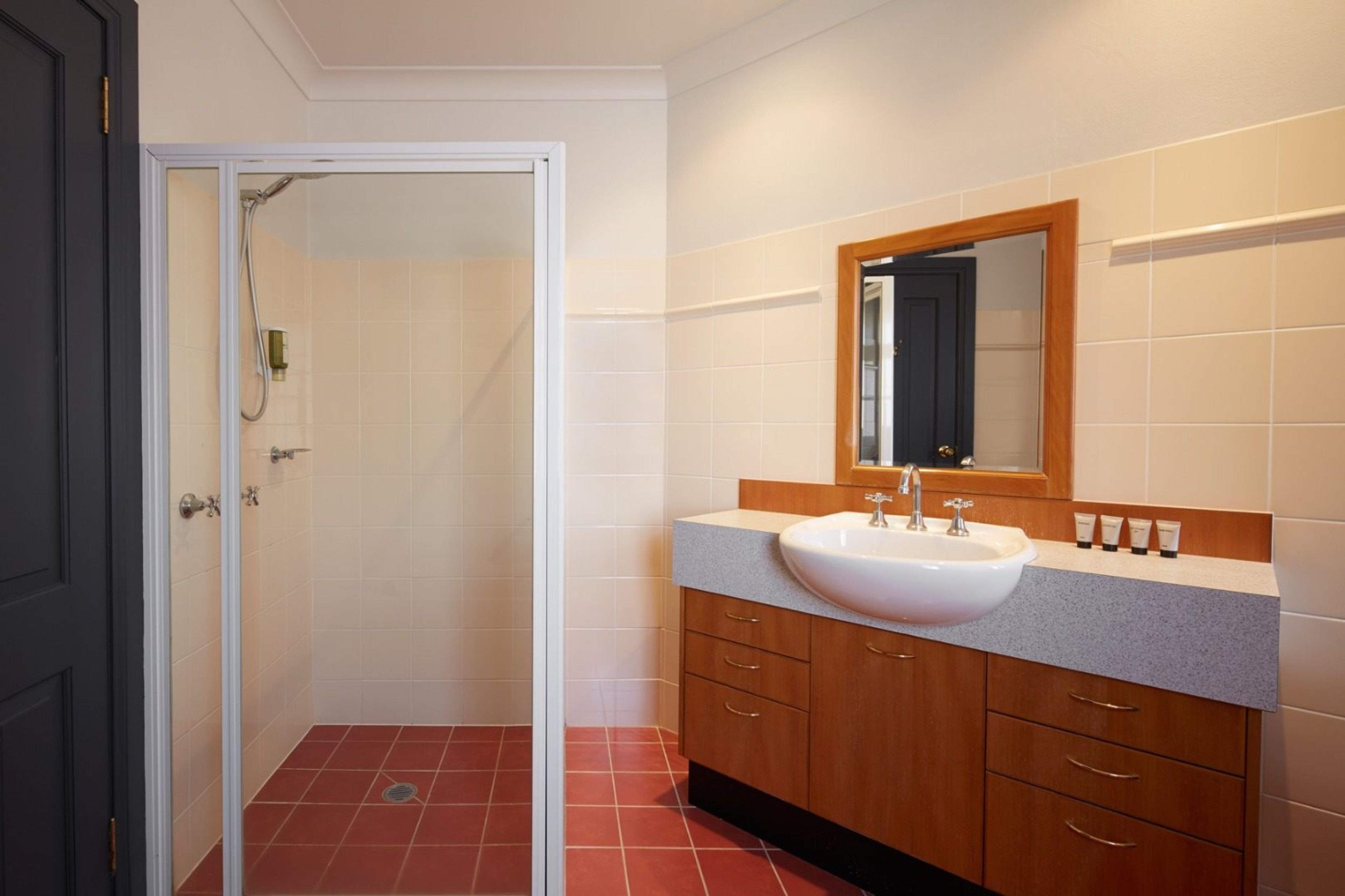 A bathroom with a white sink, wooden cabinets, and a mirror above the sink.