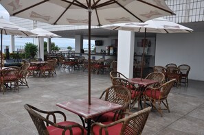 An outdoor cafe with wicker tables and chairs, umbrellas, and a view of the sea. - Marina Park (Fortaleza)