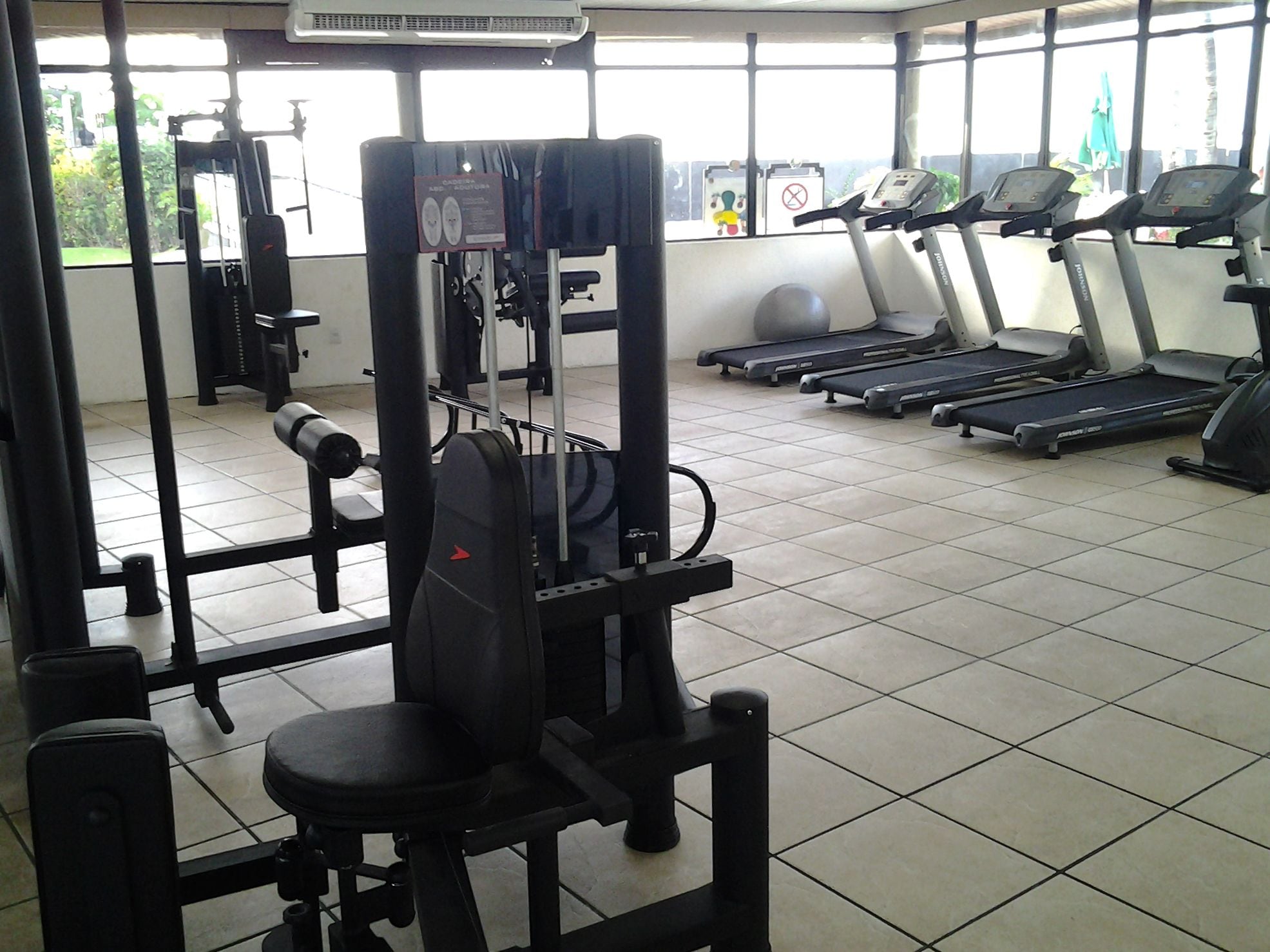 Un gimnasio con equipo de ejercicio, incluyendo un rack para sentadillas, bancos y cintas de correr.