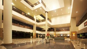 A spacious, multi-level atrium with a central column, glass railings, and a reception area. - Marina Park (Fortaleza)