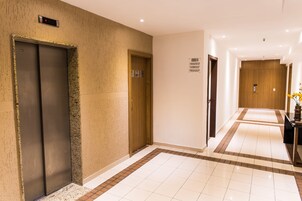 A hotel corridor with an elevator, a wooden door, and a sign with symbols.