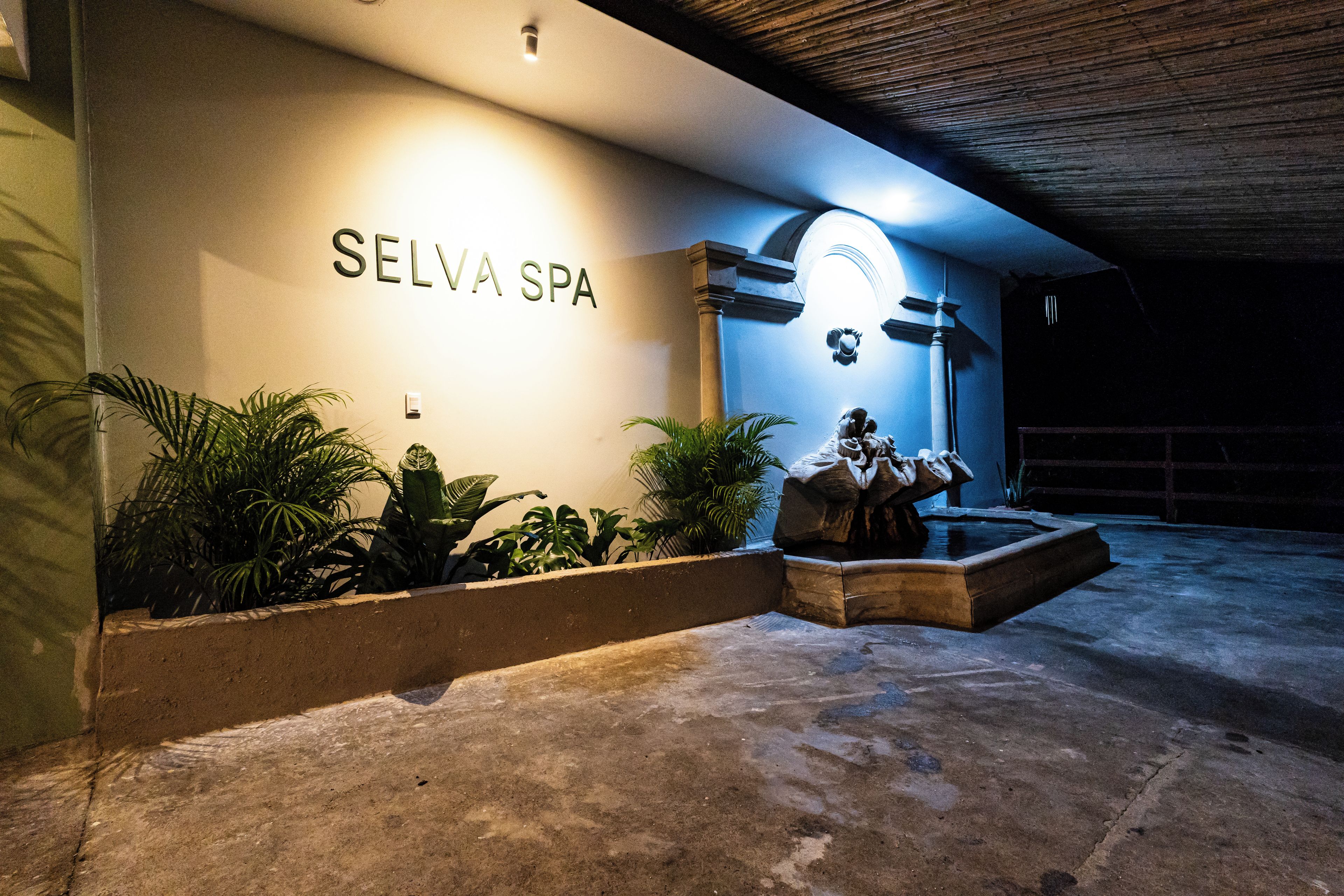A spa entrance with a sign reading 'SELVA SPA' and a stone sculpture.