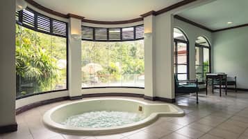 A spa area with a hot tub, large windows, and a view of the outdoors.