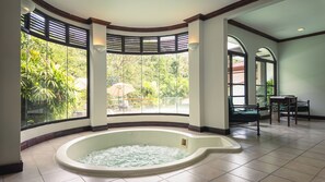 Un espace spa doté d’un bain à remous, de grandes fenêtres et offrant une vue sur l’extérieur.