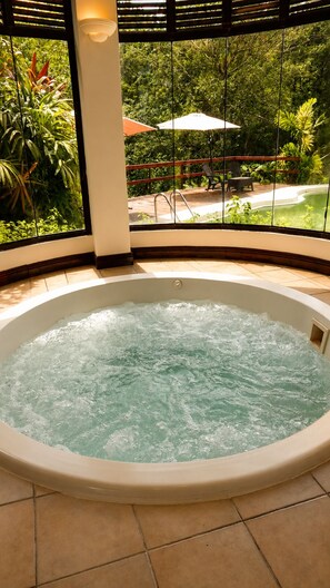 A hot tub with a view of a patio area with outdoor furniture and plants.
