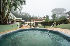 A swimming pool with a tiled edge, surrounded by a green wall and palm trees. - Hotel El Tucano Resort & Thermal Spa (La Palmeria)