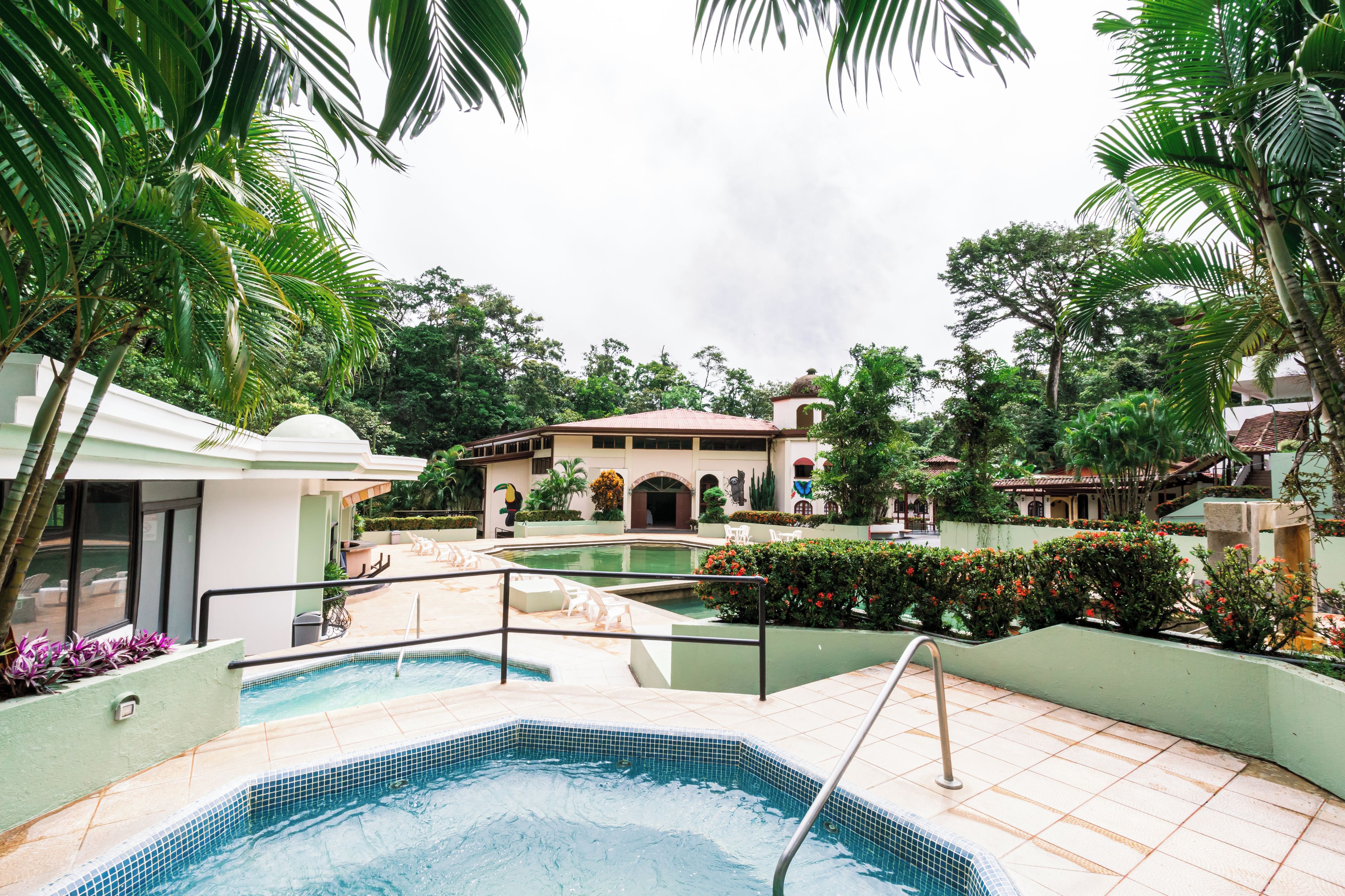 A swimming pool area with a hot tub, lounge chairs, and a building with a dome roof.