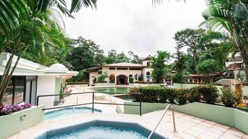 A swimming pool area with a hot tub, lounge chairs, and a building with a dome roof.