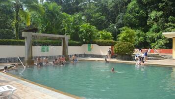 A swimming pool surrounded by lush greenery, with people enjoying the water.