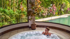 A woman in a hot tub with a view of lush greenery and a pool outside. - Hotel El Tucano Resort & Thermal Spa (La Palmeria)
