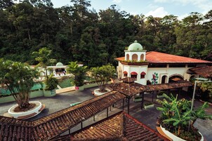 Un hotel con un patio central, piscina y un edificio con cúpula y tejado rojo.
