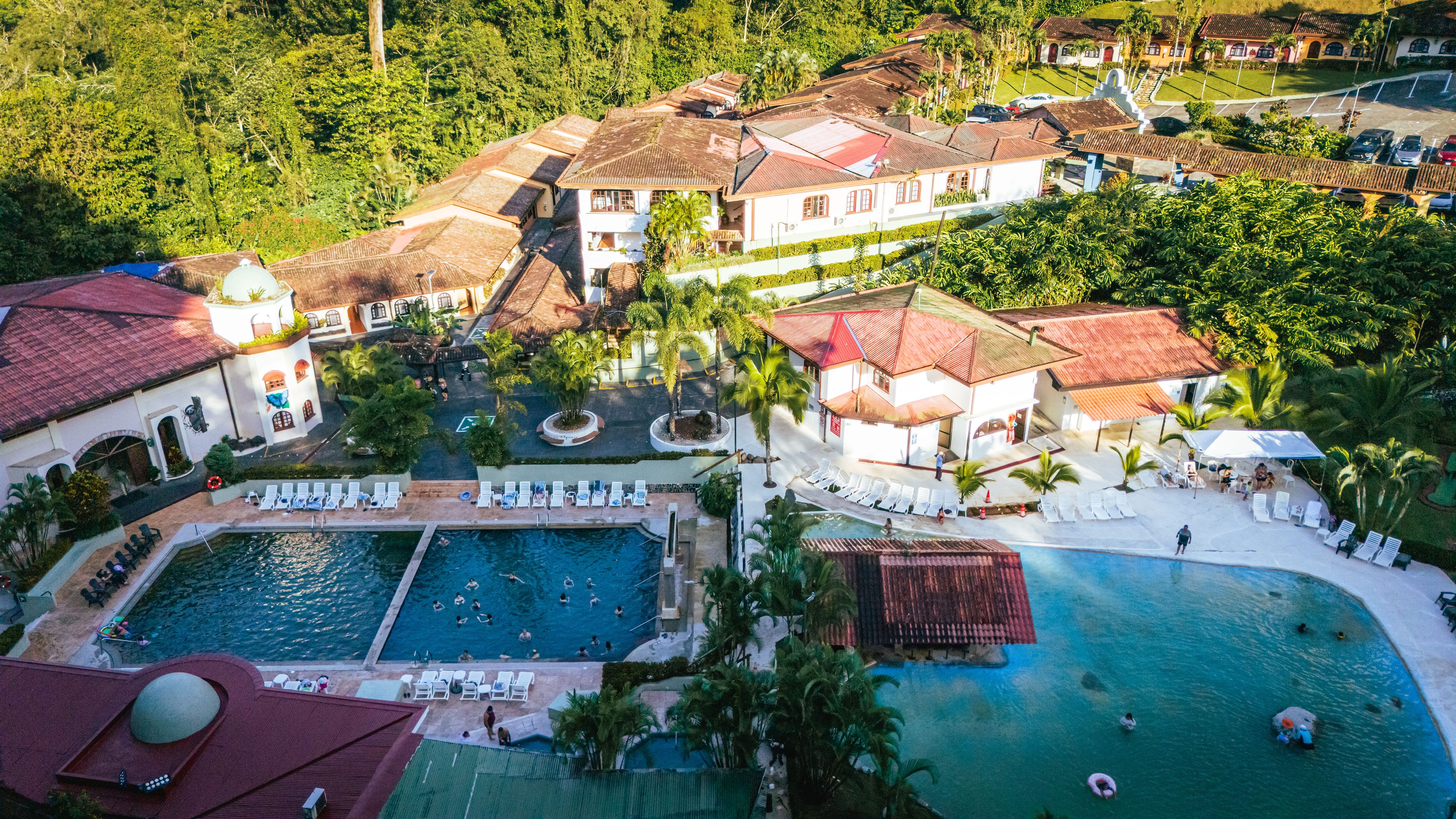 A resort with multiple swimming pools, sun loungers, and a central courtyard.