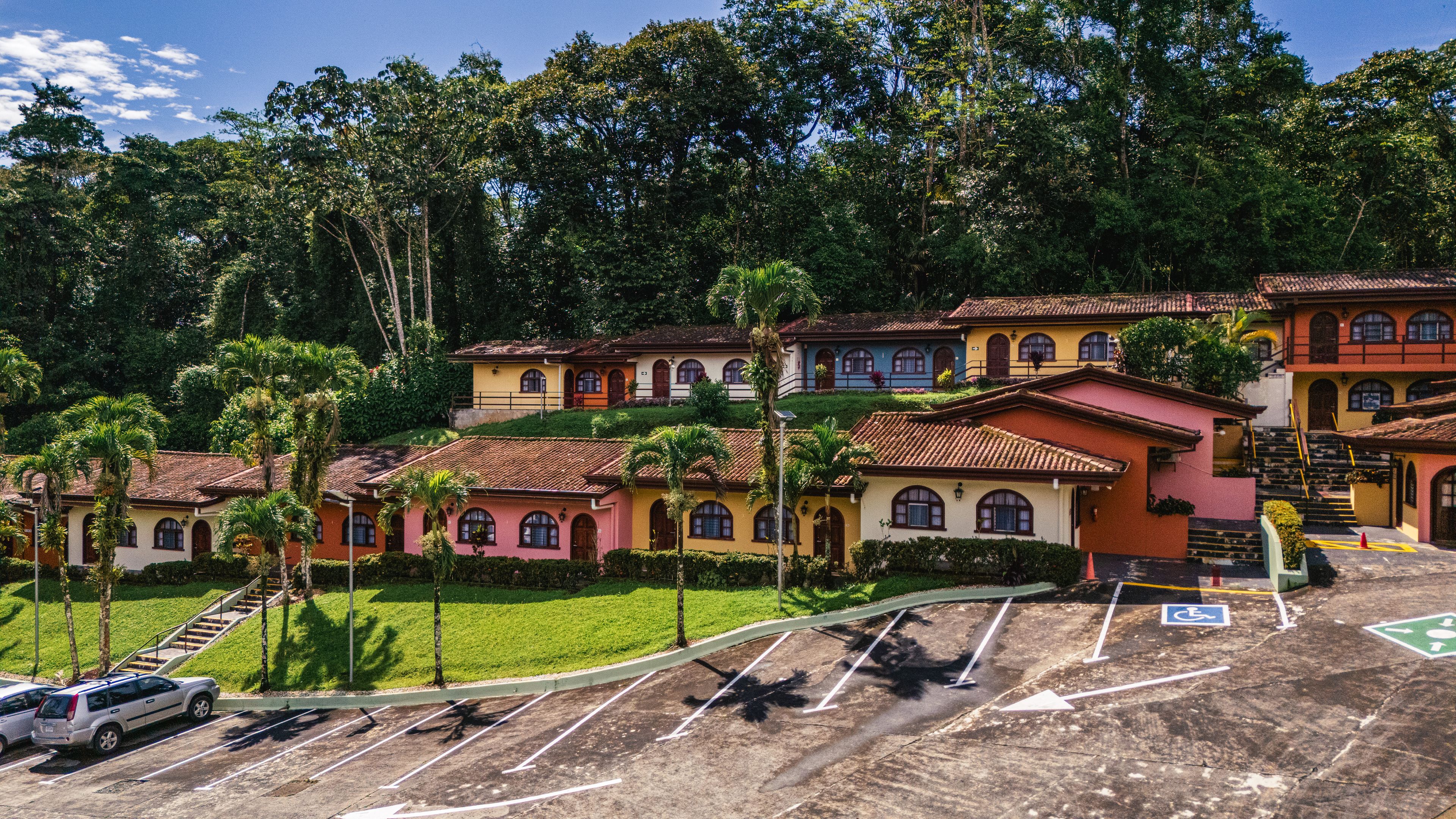 A residential area with colorful houses, a parking lot, and a staircase leading to a hilltop.