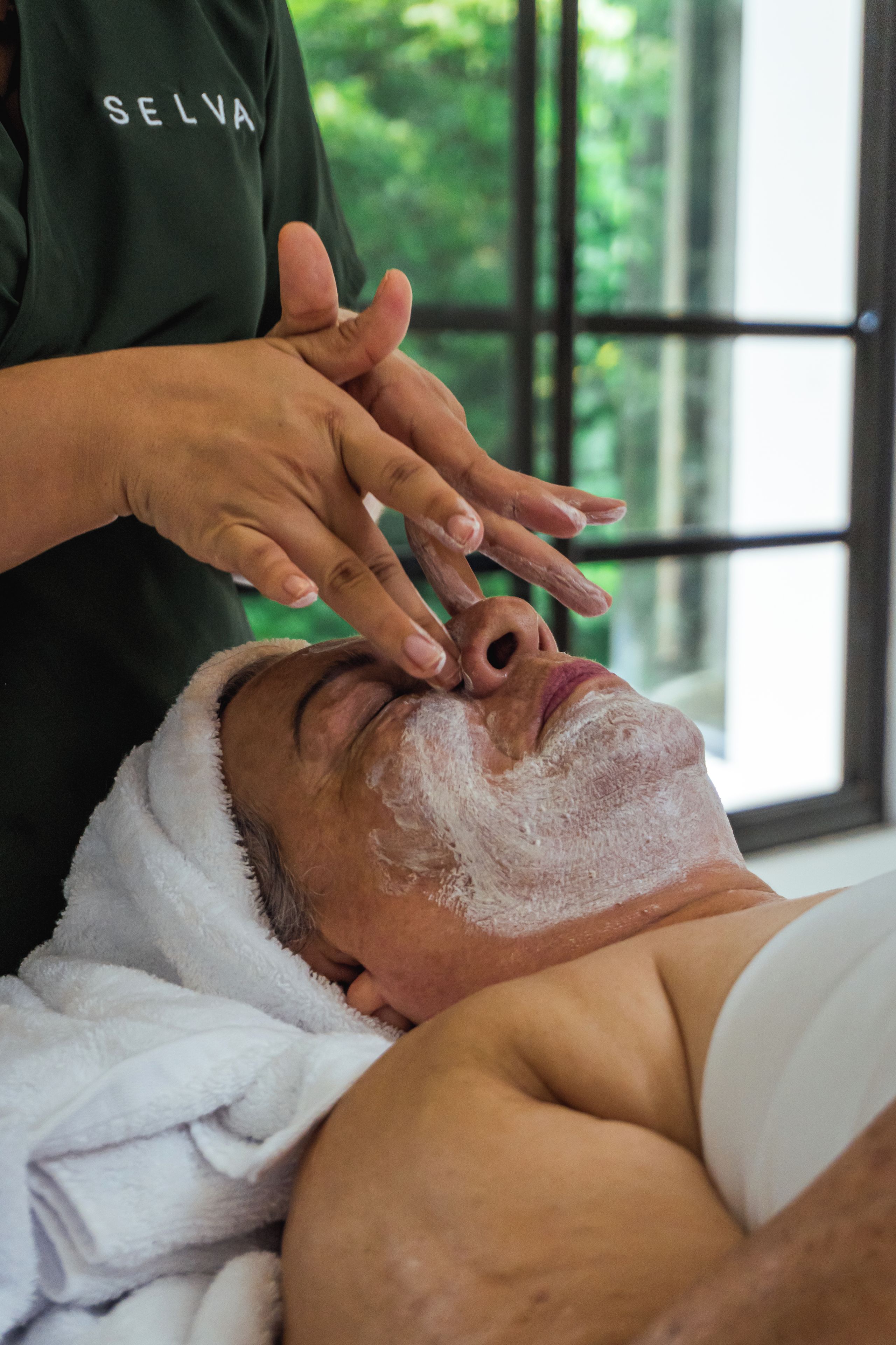 A person receiving a facial treatment with a towel wrapped around their head.