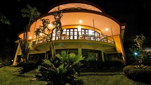 A large, circular building with a balcony, surrounded by well-maintained gardens and trees. - Hotel El Tucano Resort & Thermal Spa (La Palmeria)
