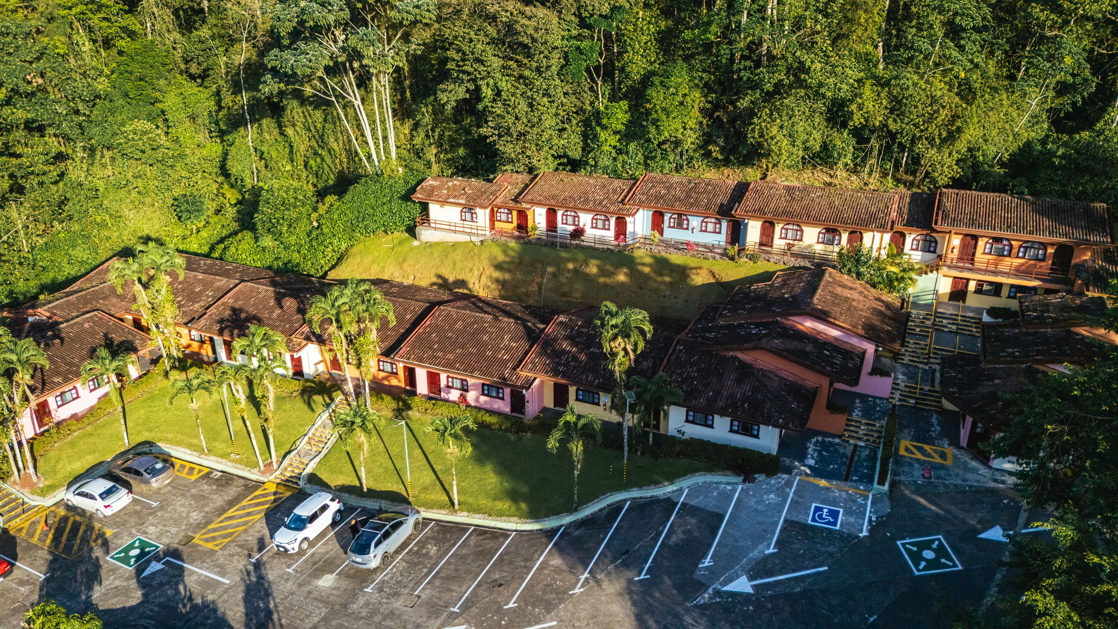 Un edificio de varios pisos con estacionamiento y un pequeño jardín.