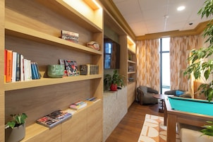 Una habitación acogedora con estanterías de madera llenas de libros, una mesa de billar y una zona de estar confortable.