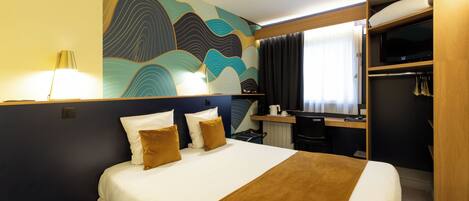 Habitación de hotel con cama, escritorio, armario y un gran mural abstracto en la pared.