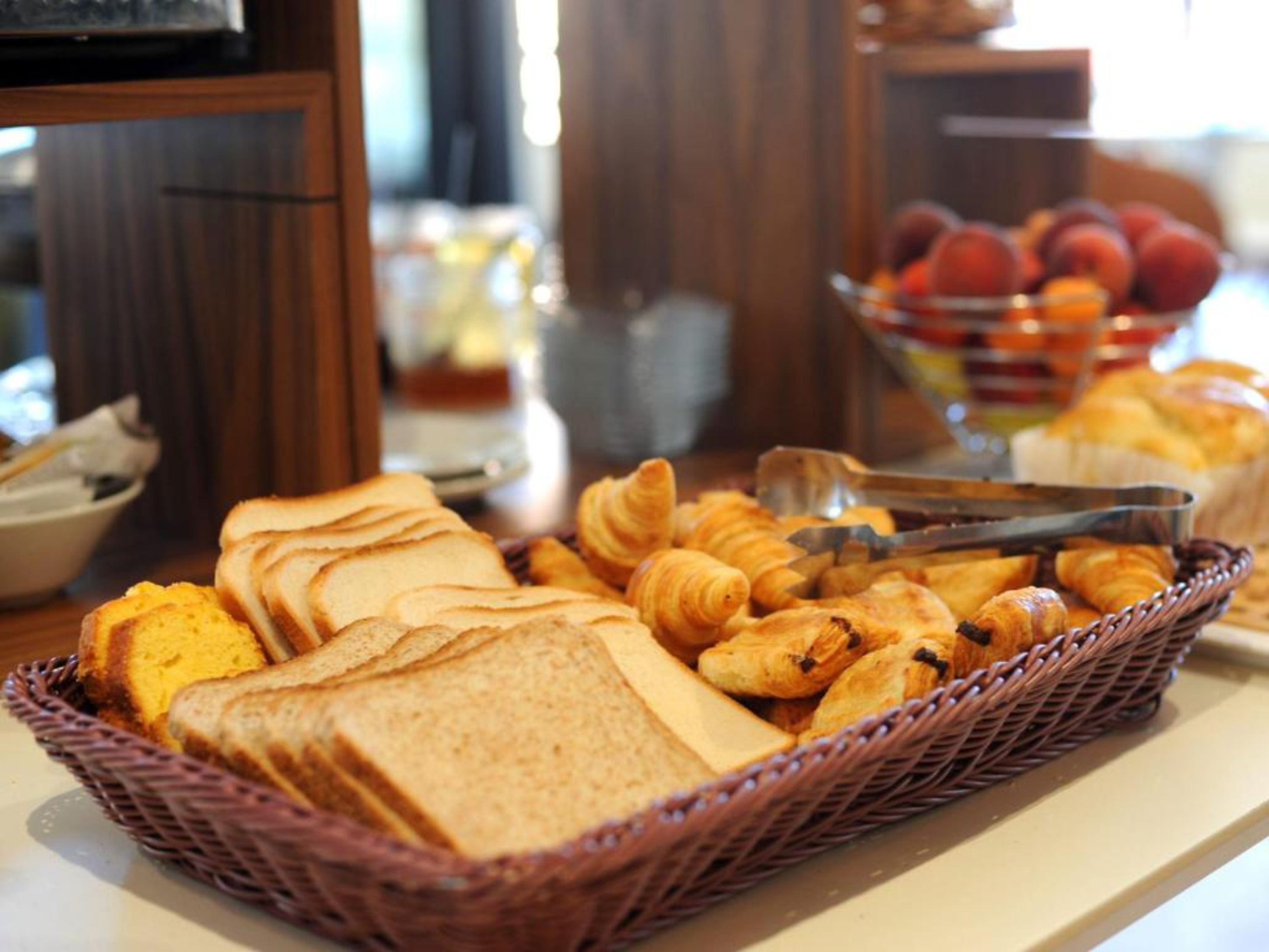 A buffet with bread, croissants, and fruits.