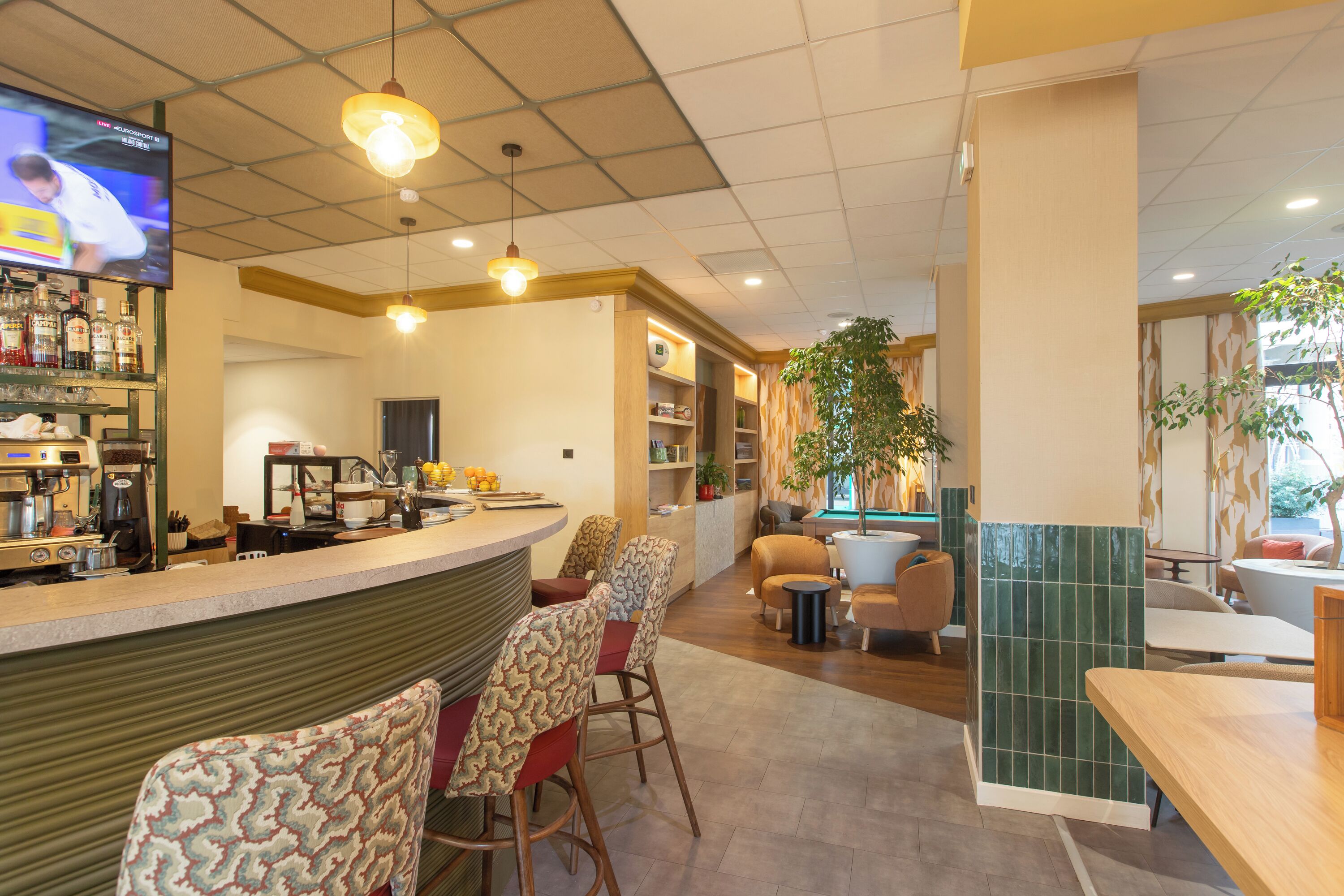 L'intérieur d'un restaurant, avec un bar, des tables et un écran de télévision.