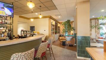 L'intérieur d'un restaurant, avec un bar, des tables et un écran de télévision.