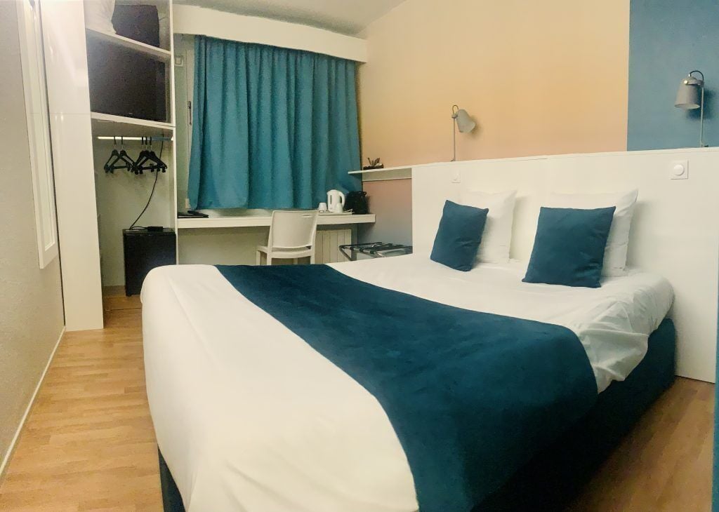 A bedroom with a bed, a desk, and a wardrobe.