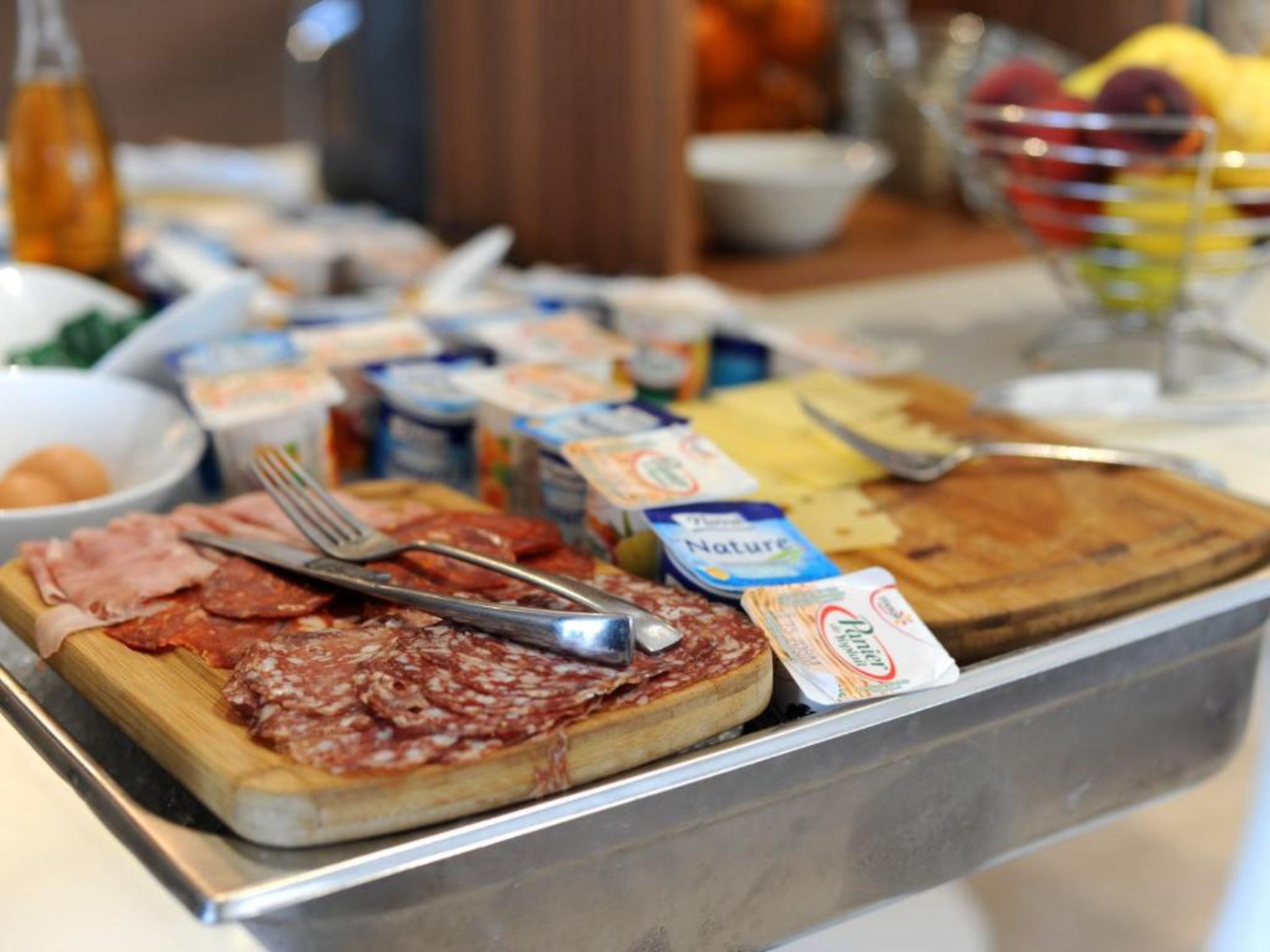 A buffet with various food items including sliced meats, cheeses, and condiments.