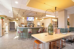 Un área de bar moderna con mostrador, taburetes y una pantalla de televisión.