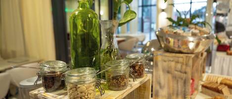 Una mesa de madera con un buffet variado, incluyendo alimentos y condimentos en frascos de vidrio.