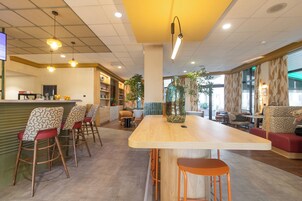 Un interior moderno con una zona de bar, asientos y un jarrón grande con plantas.