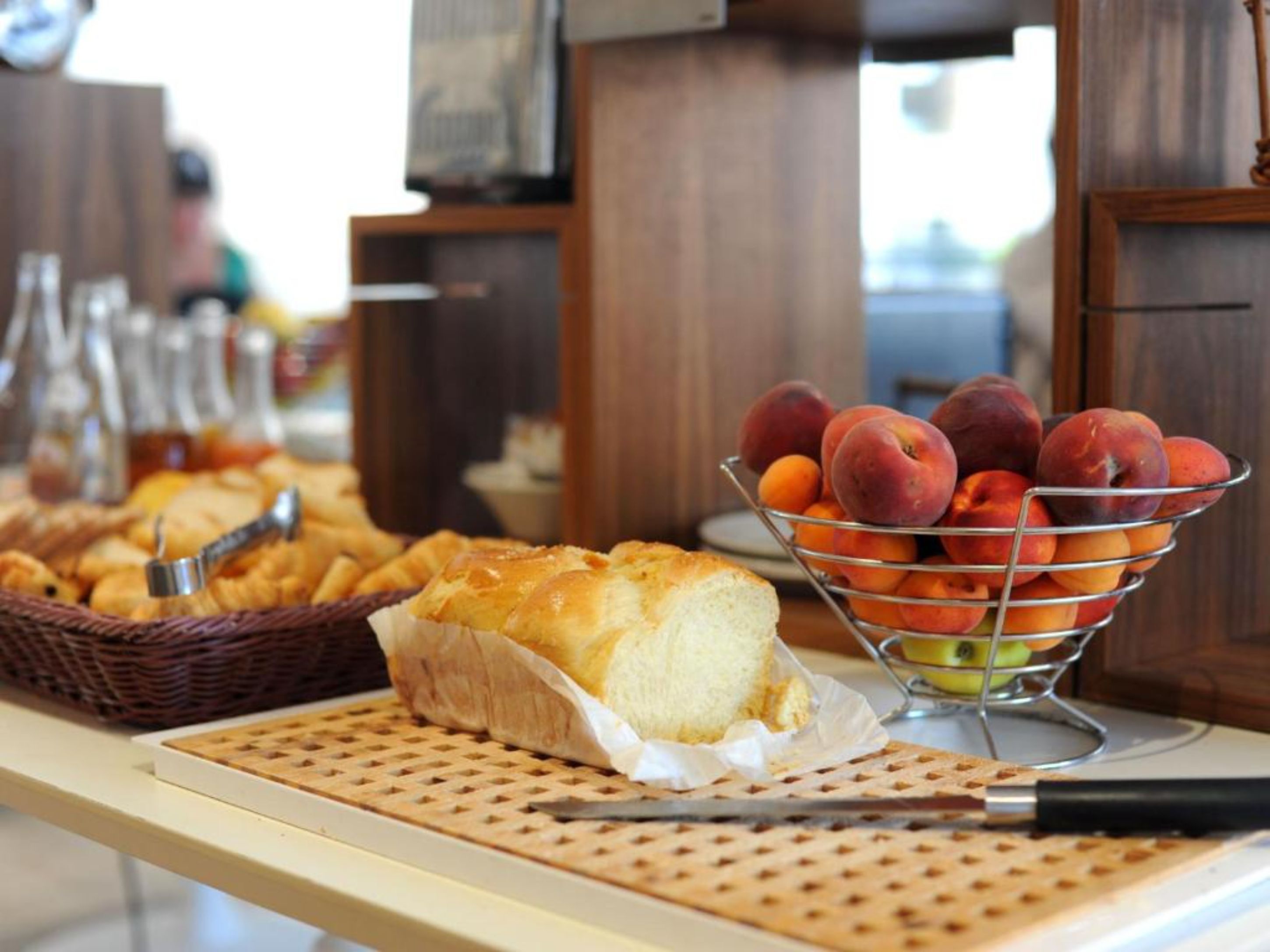 A breakfast buffet with bread, pastries, and a fruit bowl.