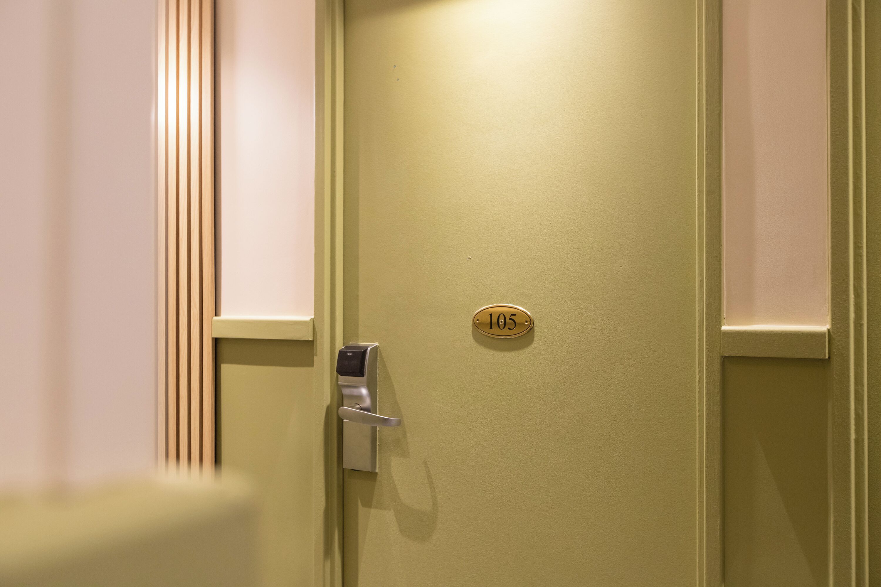 Une porte dotée d’une serrure numérique et d’une plaque indiquant le numéro de la chambre.
