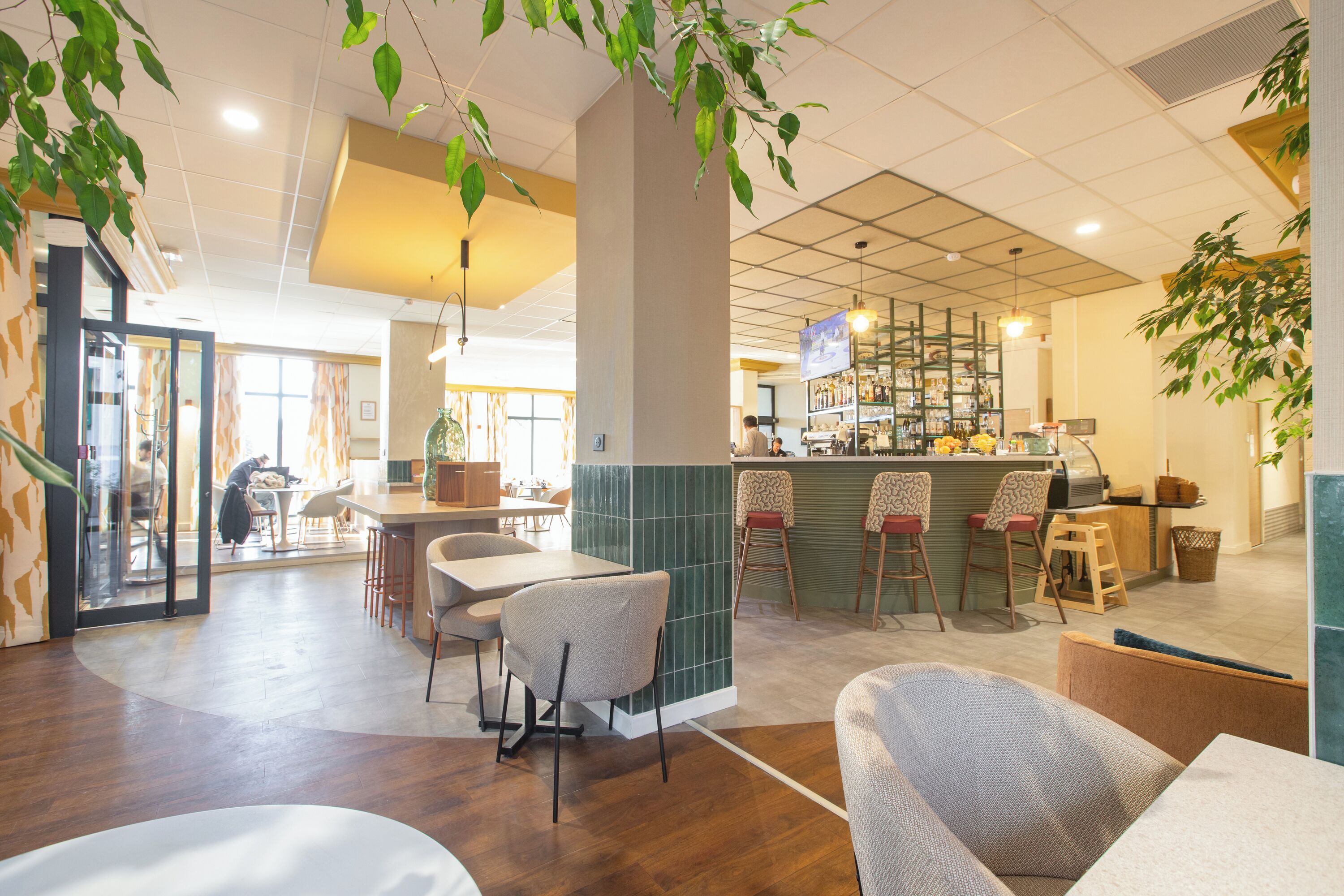 A restaurant with a bar area, wooden tables, and chairs.